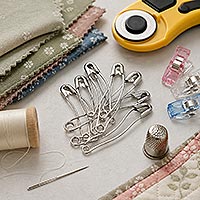 An array of curved safety pins and various other quilting notions.