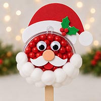 Santa Claus candy pop craft made with half of a fillable ornament, red candies, and cotton balls or pom poms for Christmas crafts, classroom parties, and holiday decorations.